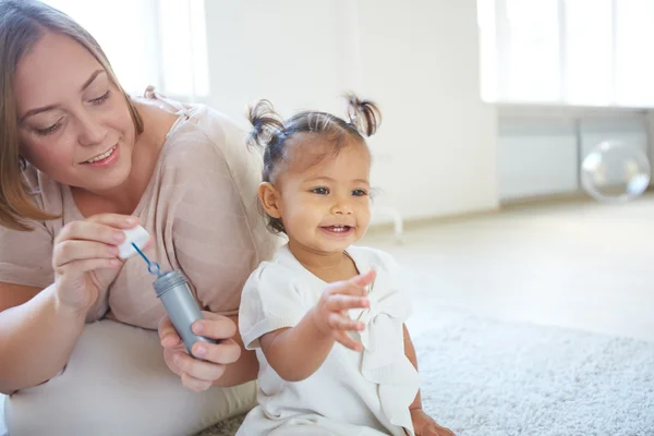 Petite fille soufflant des bulles avec la mère — Photo