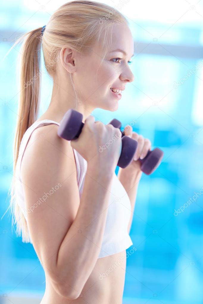 Girl lifting dumbbells in gym
