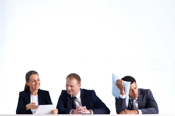 Geschäftsmann macht Mittagsschlaf, während seine Kollegen kommunizieren — Stockfoto