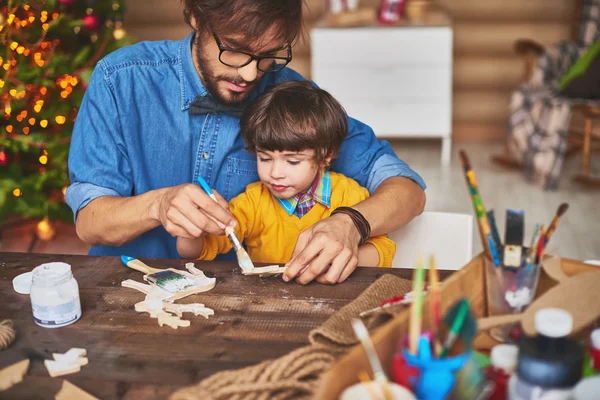 Father and son painting wooden deer — Stock Photo, Image