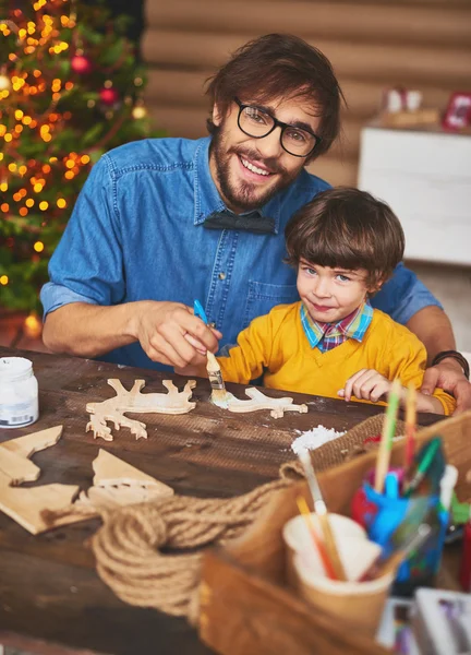 Pai e filho pintando veados de madeira — Fotografia de Stock