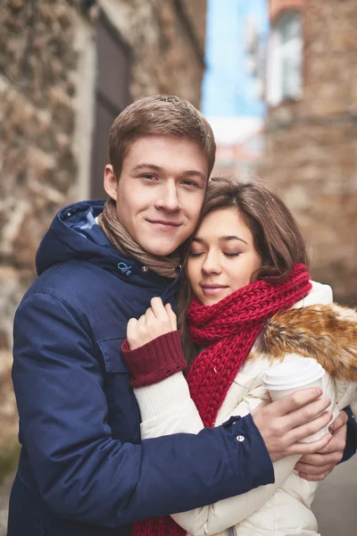 Joven hombre con café abrazando novia — Foto de Stock