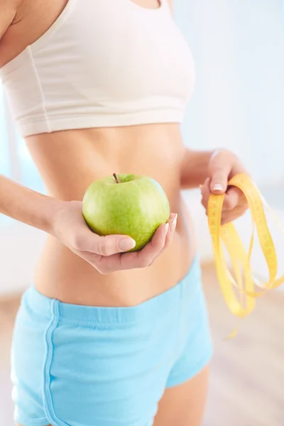 Mujer sosteniendo manzana y cinta métrica — Foto de Stock