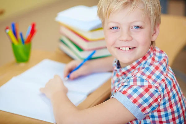 Schoolboy escrevendo em copybook — Fotografia de Stock