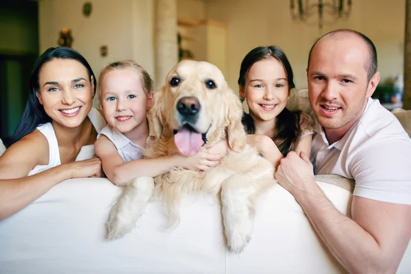 Семья с собакой отдыхает на диване — стоковое фото