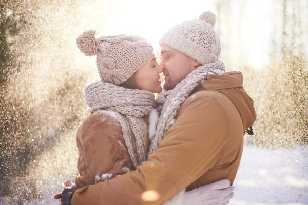 Loving couple kissing in snowfall — Stock Photo, Image