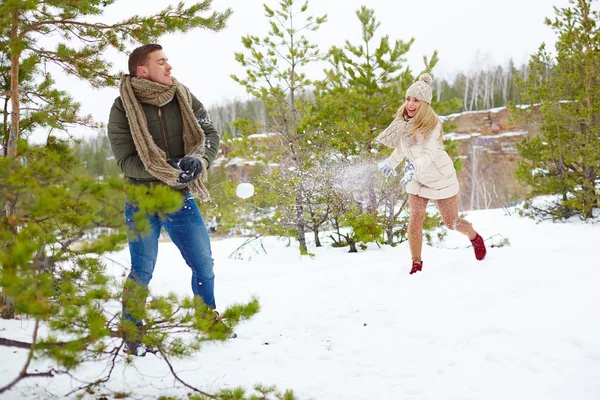 Paar spelen sneeuwballen in park — Stockfoto