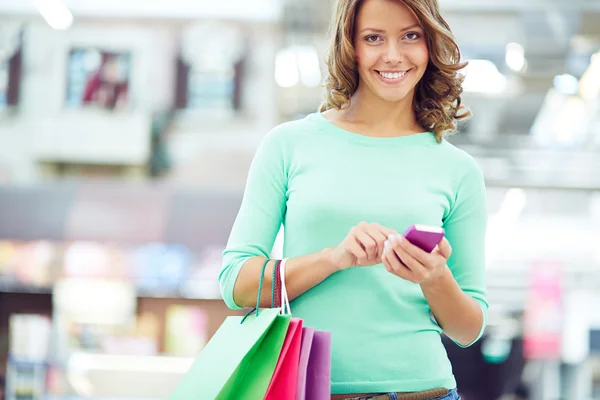 Frau mit Einkaufstüten per Smartphone — Stockfoto