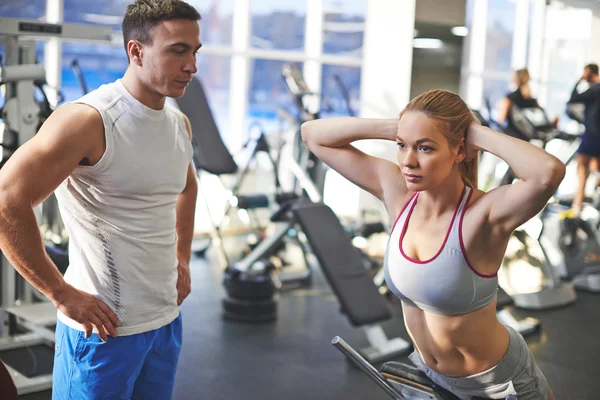 Vrouw trainen in de fitnessruimte met trainer — Stockfoto