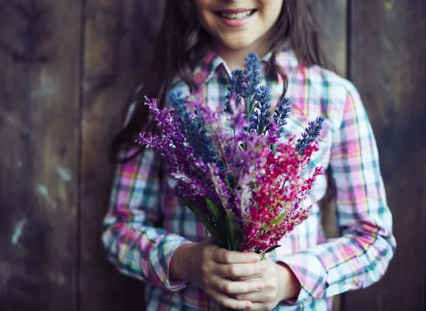 Menina segurando um monte de flores silvestres — Fotografia de Stock