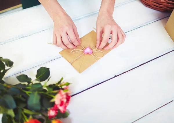 Mãos amarrando nota de amor no envelope — Fotografia de Stock