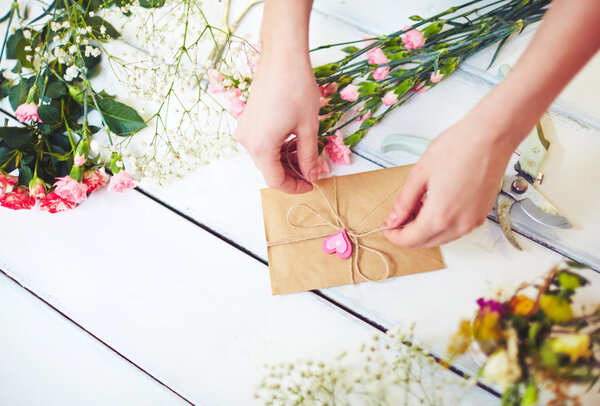 Hands tying love note in envelope