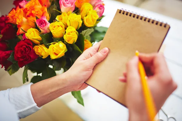 Florist med penna att göra anteckningar — Stockfoto