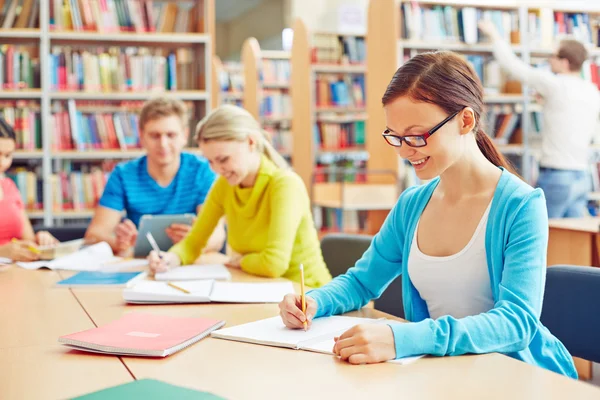 Estudiante haciendo notas en la biblioteca universitaria — Foto de Stock