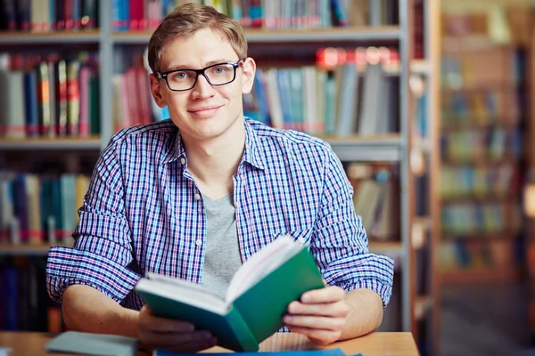 Hombre sentado en la biblioteca con libro — Foto de Stock