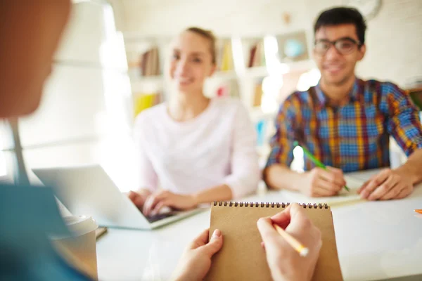 Estudante fazendo anotações com colegas de grupo — Fotografia de Stock