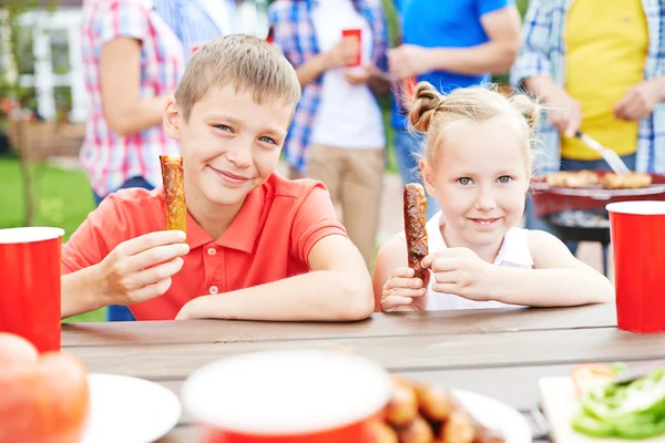 Frère et sœur mangeant des saucisses — Photo