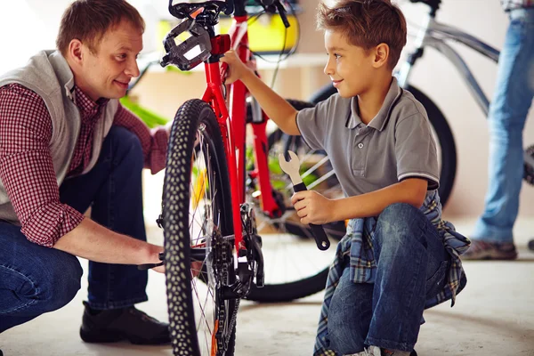 Padre mostrando hijo cómo reparar bicicleta — Foto de Stock