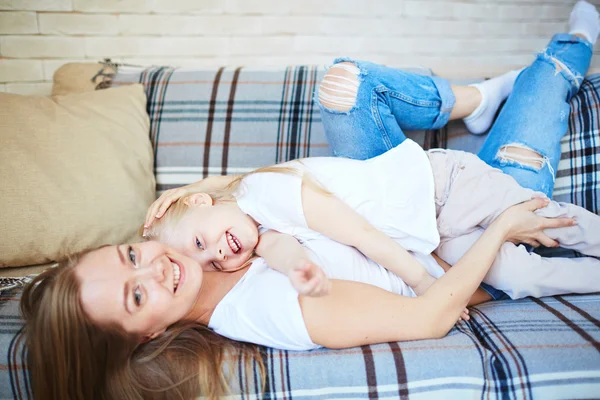 Meisje en haar moeder ontspannen op de sofa — Stockfoto