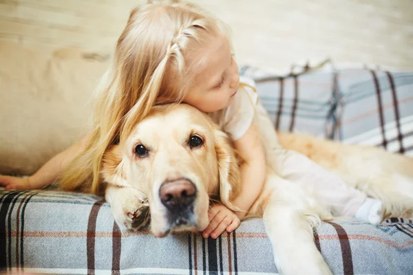 Маленькая девочка обнимает собаку — стоковое фото