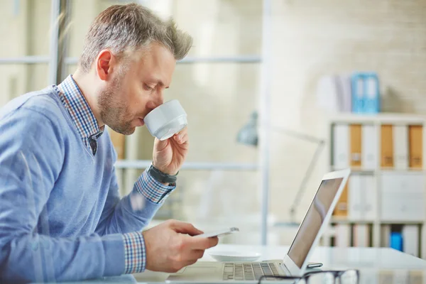 Empresario beber té mientras lee sms — Foto de Stock