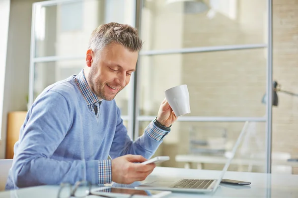 Empresario con taza de café leyendo sms —  Fotos de Stock