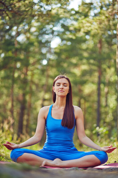 Женщина сидит в позе лотоса
