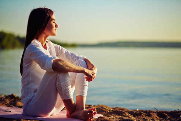 Serene woman sitting on sandy beach