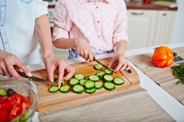 Woman and girl cutting cucumber — Stock Photo, Image