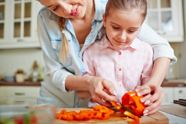 Girl cutting pepper with help of mother — Stock Photo, Image