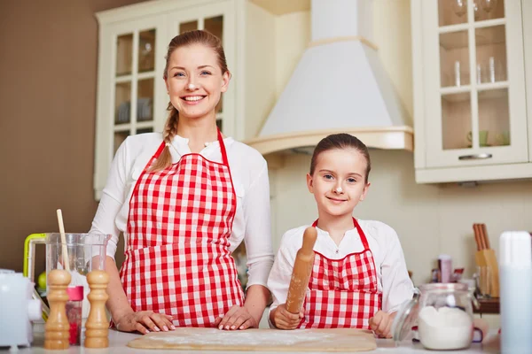 Tjej och mamma i förkläden kommer för att göra degen — Stockfoto