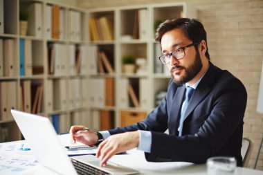 Ofiste dizüstü bilgisayar kullanan bir iş adamı