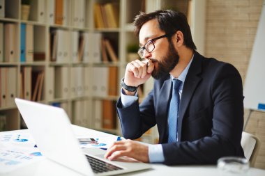 Ofiste dizüstü bilgisayar kullanan bir iş adamı
