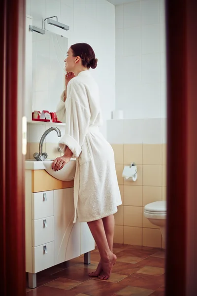 Женщина в халате смотрит в зеркало — стоковое фото