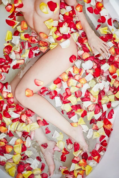 Mujer tomando baño con pétalos de rosa — Foto de Stock