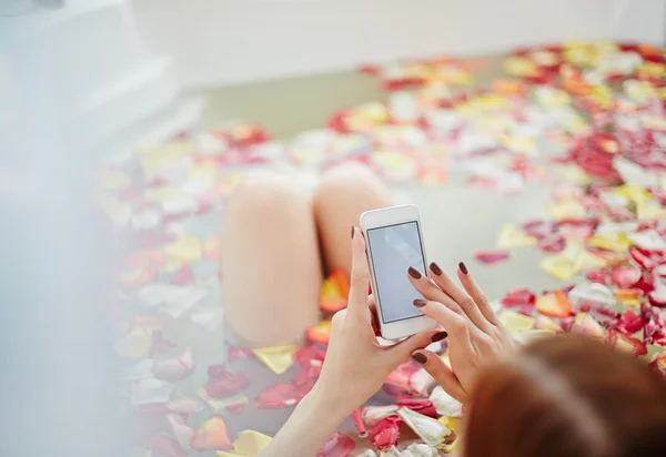 Mulher usando smartphone durante o procedimento de spa — Fotografia de Stock