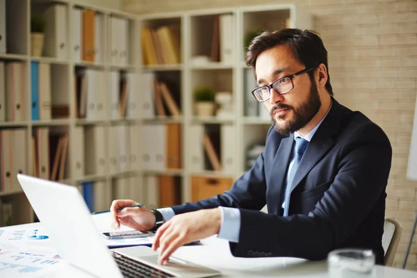 Uomo d'affari che utilizza laptop in ufficio — Foto Stock