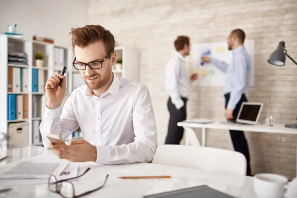 Homme d'affaires écrivant sms dans l'environnement de travail — Photo