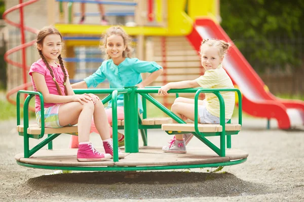 Friendly girls riding on carousel — Stock Photo, Image