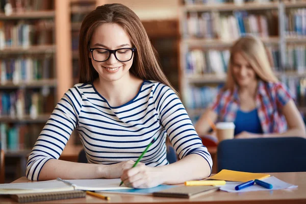 Chica en gafas haciendo notas en la lección — Foto de Stock