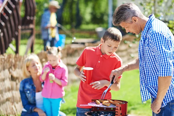 Father and son frying sausages on grill — Stock Photo, Image