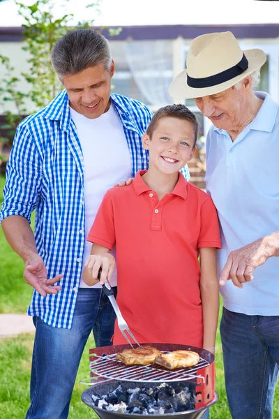 Familie kocht Fleisch auf dem Grill — Stockfoto