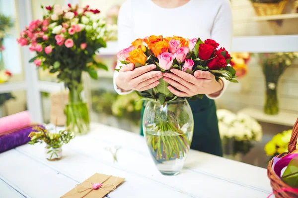 Floristería femenina sosteniendo rosas en jarrón — Foto de Stock