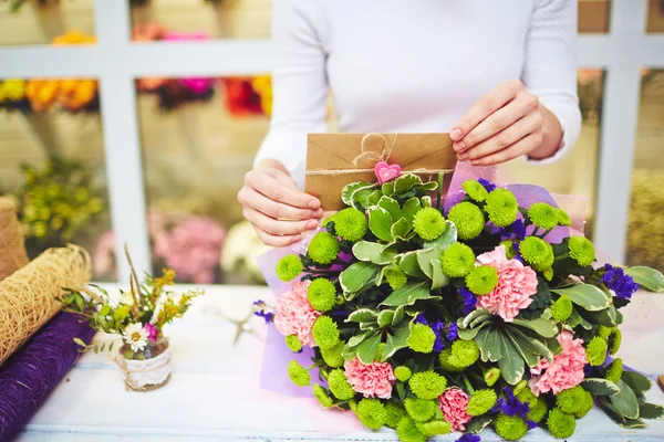 Florist putting envelope in bouquet — Stock Photo, Image