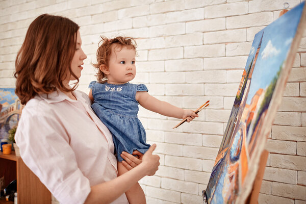 mother and little daughter looking at painting