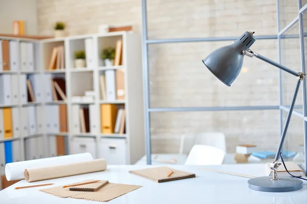 Skrivbord med lampa, papper och pennor — Stockfoto