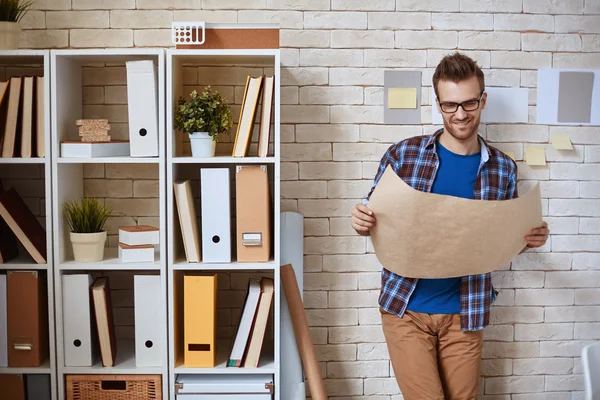 Architect met blauwdruk staande door muur — Stockfoto