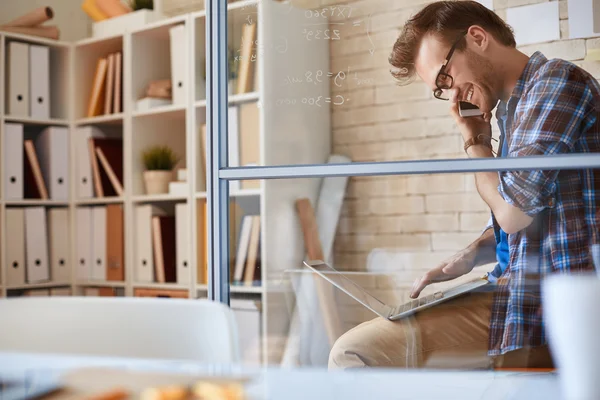 Businessman speaking on phone while networking — Stock Photo, Image