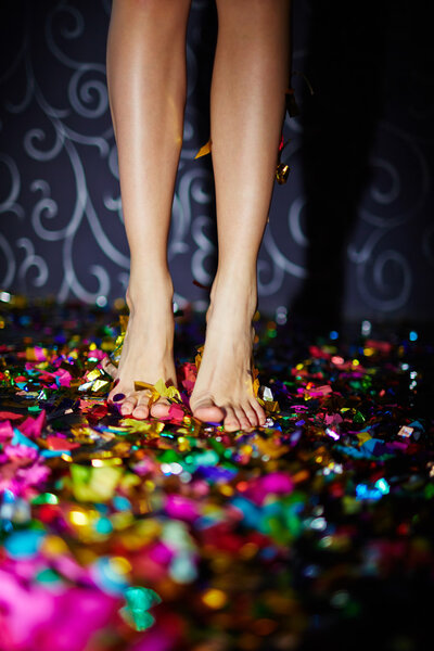 Barefoot female feet on confetti