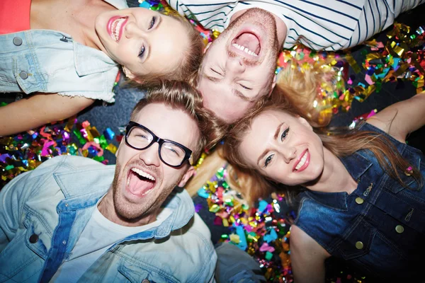 Joyful friends lying on floor in nightclub — Stock Photo, Image